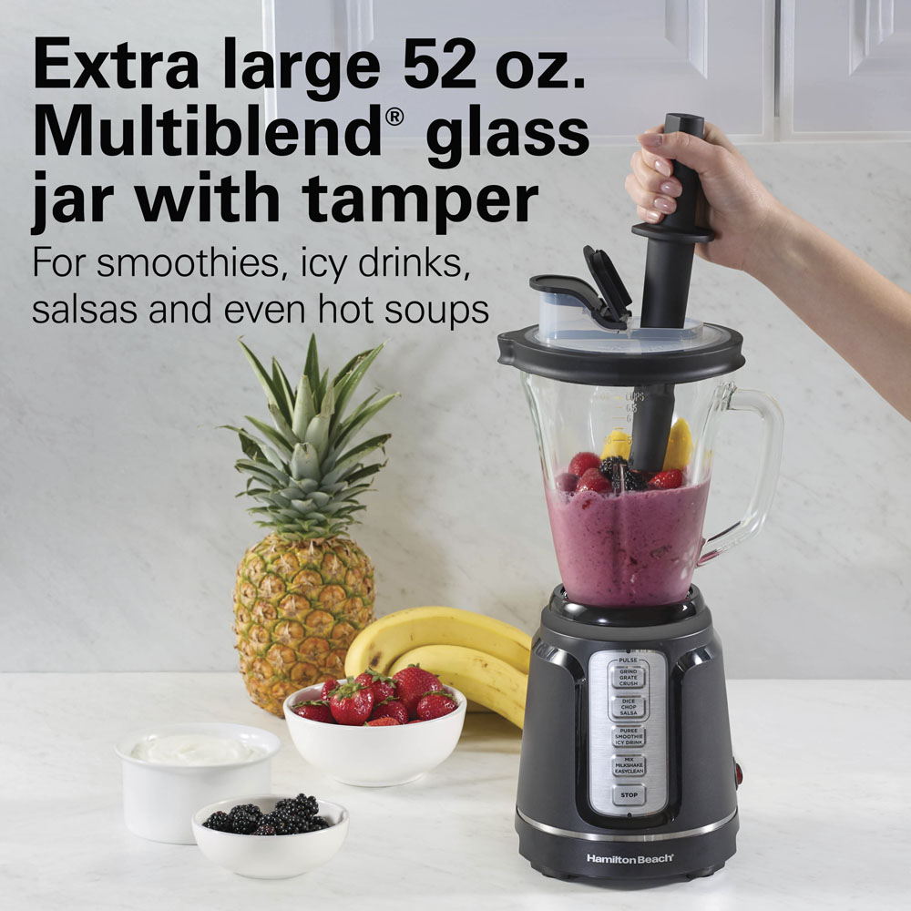 Manufacturer image of the black Hamilton Beach PowerBlend Duo 54500J with 52-ounce glass pitcher and tamper; styled ingredients do not verify package contents.
